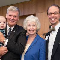 President Thomas J. Haas holding a baby with his wife Marcia Haas, and a guest at the Arend and Nancy Lubbers Student Services Center Dedication